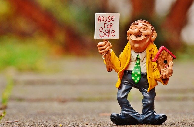 model of a man holding a house for sale sign