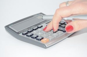 a lady's hand holding a pen and using a calculator