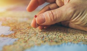 hand holding a pin above a map