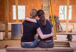 2 ladies with their arms around each other infront of a room which is being renovated
